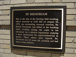 A plaque reads: "In memoriam. This is the site of the Sterling Hall Bombing, which occurred at 3:40 AM on August 24, 1970. An outstanding research scientist, Dr. Robert Fassnacht, was killed in the bombing while working in his laboratory on a physics experiment studying a basic mechanism for superconductivity in metals. Three others were injured. Dr. Fassnacht was 33 years old, married, and had three young children."
