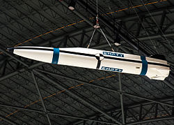 White missile with blue and black stripes hanging from a roof