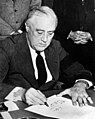 Very similar image showing Roosevelt signing the declaration of war against Japan, three days earlier.