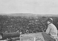 An American soldier looks out at thousands of German prisoners