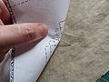 Sewing a tailor's tack with thread to mark a pattern on fabric before cutting the fabric