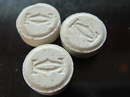 Three off white coloured ecstasy pills set against a black background