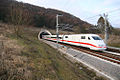 White electric train with red cheatline emerging from tunnel in the countryside (from Transport)