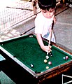A child plays a miniature billiard table set on a coffee table and using small balls.