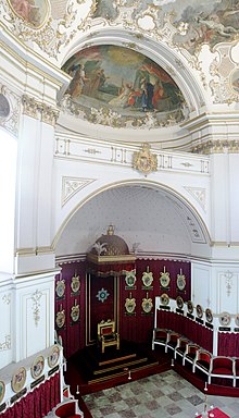 Frederick I's throne (bottom center) in the Ordenskapelle and its semidome. Coats of arms for members of the Order of the Golden Eagle line the walls above their seats.