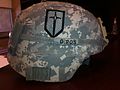 Half scale insignia of the 1st Maneuver Enhancement Brigade worn on the right side of an Advanced Combat Helmet.