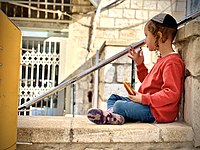 A haredi boy eats a sufganiyah in the old city of Safed.