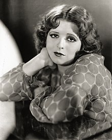 A black-and-white, soft-focus shot of a dolled-up young woman with short dark hair wearing a polka dot top.