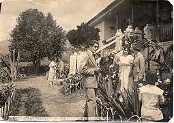Black and white photo showing people in a garden outside a house