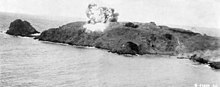 Black and white photograph showing a large explosion on an island