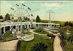 A color image of an amusement park from the early 20th century, showing several rides, including a Ferris wheel