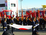 Firefighters in Tokyo holding the Japanese national flag during a ceremony