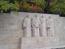 A stone wall with the sculptures of four bearded men