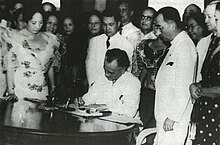 Quezon signing the Women's Suffrage Bill in front of a large group of people