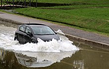 A car is passing through shallow water