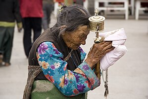 Tibetan woman with a prayer wheel praying