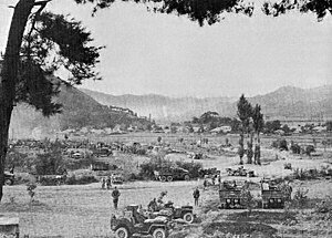 Trucks depart for a distant battlefield in the mountains where explosions can be seen