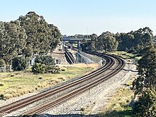 Long shot of a dual track freight railway to the left of a tunnel portal