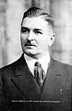 A black-and-white photograph of a man in a suit with a tie.