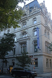 A view of the Warburg House's Fifth Avenue facade. The first through fourth stories are clad in limestone, while the fifth and sixth stories contain dormer windows that project from a mansard roof. Some of the windows have elaborate frames.