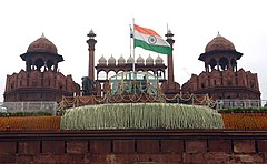 The national flag of India hoisted on a wall adorned with domes and minarets.