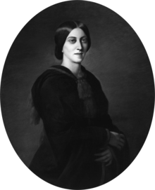 Three-quarter oval portrait of a slender woman aged about 30, garbed in black. Her deep-set eyes gaze solemnly over the viewer's shoulder. Her dark, straight hair is parted in the centre without a fringe, combed over the ears, and pulled back in a low bun.