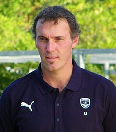 A middle aged man, wearing a dark blue top