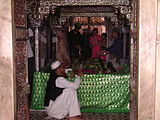 An ulama in front of the tomb