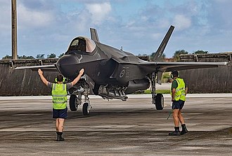 Front three-quarter view of F-35 Lightning II with two ground crew in foreground