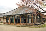 Wooden building with pyramid shaped roof and white walls.
