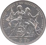 Seated Helvetia and Ticino. Helvetia is holding a sword and shield bearing the Swiss cross; Ticino is holding an oar with cantonal colours. The figures are seated above a the Gotthard tunnel with a steam engine emerging. Legend along edge at top, denomination at bottom.