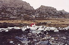 A cross amongst rocks painted white and a mountain in the background