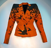 An orange jacket printed with black birds, laid flat on a surface.