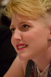 Porträt einer Person mit kurzen blonden Haaren.