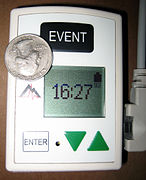 A Holter monitor with a US quarter dollar coin to show scale