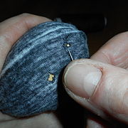mushroom wrapped in a fine knit cloth with holes in it; hand holding needle