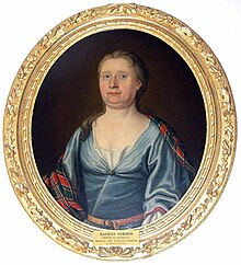 Oil painting of a middle-aged woman in a blue white dress with brown leather belt, with a plaid around her shoulders of a red-and-blue tartan with thin white over-checks