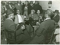Photo of patrons sitting around a table in a juke joint in Clarksdale, Mississippi, in 1939