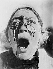 A woman with broken glasses and blood running down her face.