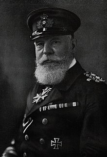 Black and white bust photo of a man wearing a mustache and white beard in military garb.