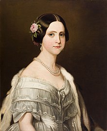 Half-length painted portrait of a young woman wearing a white satin ball gown trimmed with bows and lace, and also wearing an ermine stole thrown over one shoulder, a double strand of large pearls around her neck, pearl drop earrings, and a pink camellia arranged in the hair over her right ear.