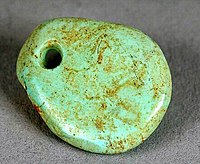A small oval pieced of turquoise with a hole drilled though the top