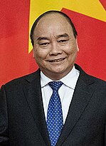 Nguyễn Xuân Phúc is seen smiling while wearing a black suit, a blue tie with white dots and a white shirt.