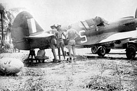 Rear three-quarter view of P-40 Kittyhawk with four men in tropical kit