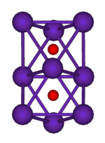 The ball-and-stick diagram shows two regular octahedra which are connected to each other by one face. All nine vertices of the structure are purple spheres representing rubidium, and at the centre of each octahedron is a small red sphere representing oxygen.
