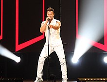 A wearing a white short-sleeved shirt and pants is performing on stage.