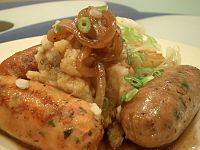 A plate of sausage and mashed potatoes, with cabbage and onion gravy, commonly known as "bangers and mash"