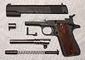 A M1911–A1 pistol disassembled and showing the locking grooves on the barrel.