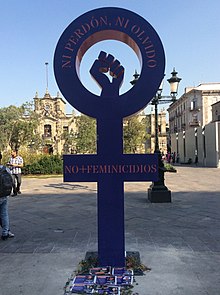 A symbol of Venus with a closed fist raised in the center. It has written the phrases "neither forgiving nor forgetting" and "no more femicides" in Spanish.