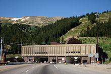Building facing a large mountain with two openings for the traffic, visible on the roof of the building are large ventilation hoods